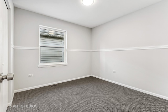 spare room featuring dark colored carpet