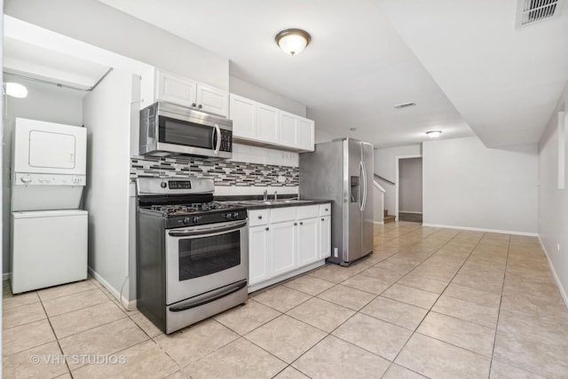 kitchen featuring tasteful backsplash, white cabinets, stainless steel appliances, and stacked washer / drying machine