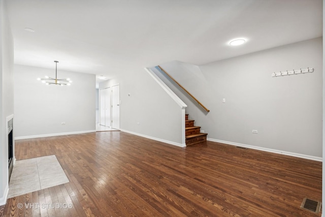 unfurnished living room with dark wood-type flooring and a notable chandelier