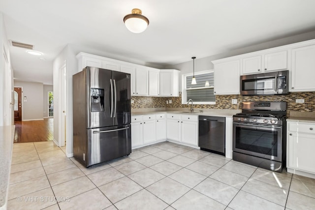 kitchen with hanging light fixtures, white cabinets, stainless steel appliances, and light tile patterned floors