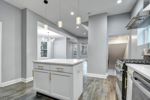 kitchen featuring a center island, white cabinets, wall chimney range hood, decorative light fixtures, and stainless steel appliances