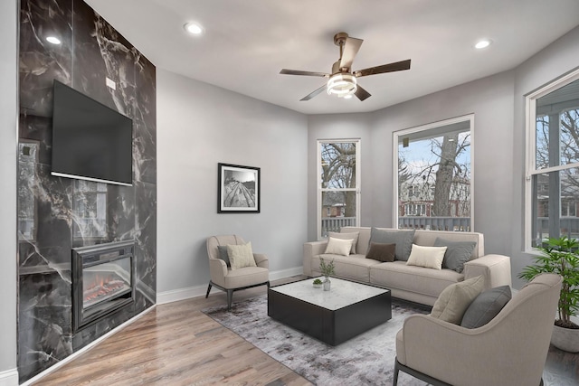 living room with hardwood / wood-style flooring, ceiling fan, and a premium fireplace