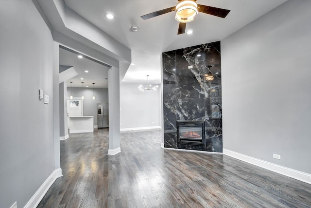 unfurnished living room with a fireplace, dark hardwood / wood-style flooring, and ceiling fan with notable chandelier