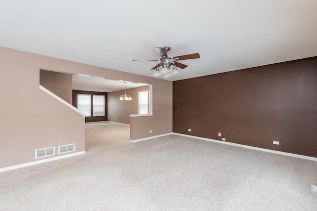 carpeted empty room with ceiling fan with notable chandelier