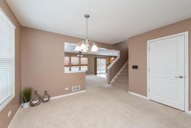 carpeted empty room with a chandelier