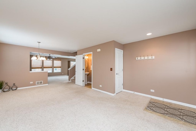 empty room with carpet flooring and ceiling fan with notable chandelier