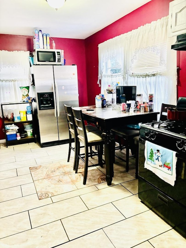 kitchen featuring stainless steel refrigerator with ice dispenser and black stove