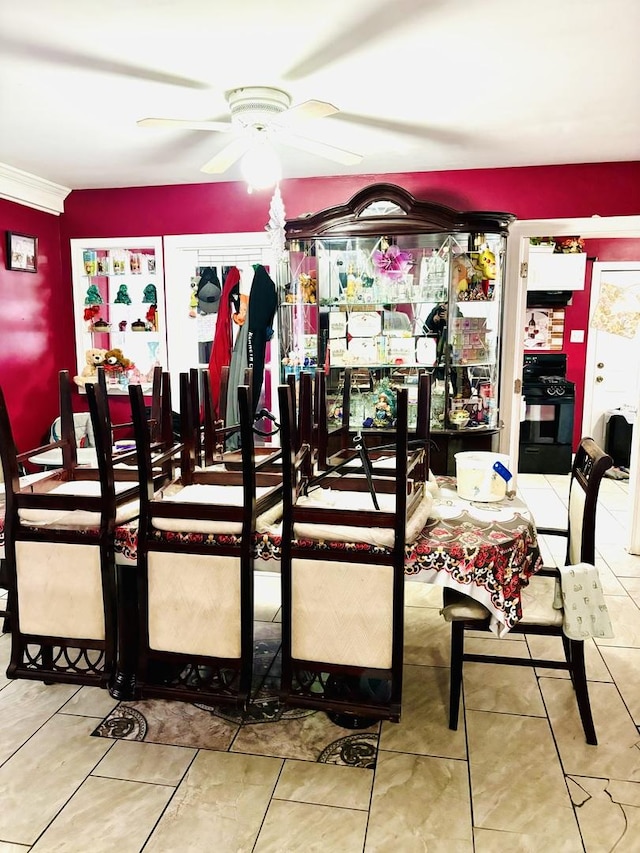 tiled dining area featuring ceiling fan and ornamental molding