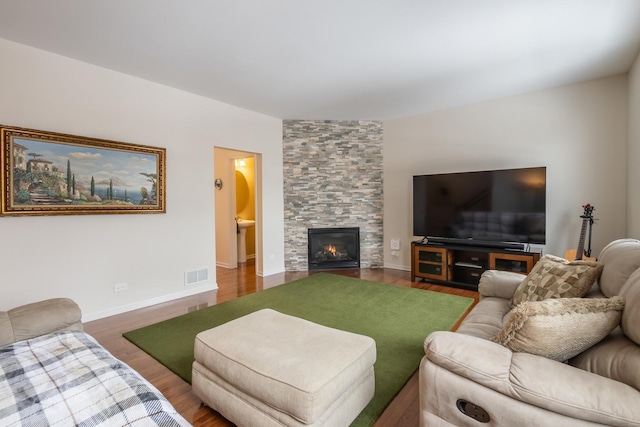 living room with a stone fireplace and wood-type flooring