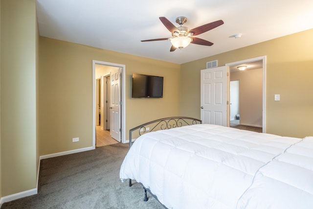 carpeted bedroom with ensuite bath and ceiling fan