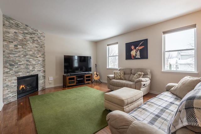 living room with dark hardwood / wood-style flooring and a stone fireplace