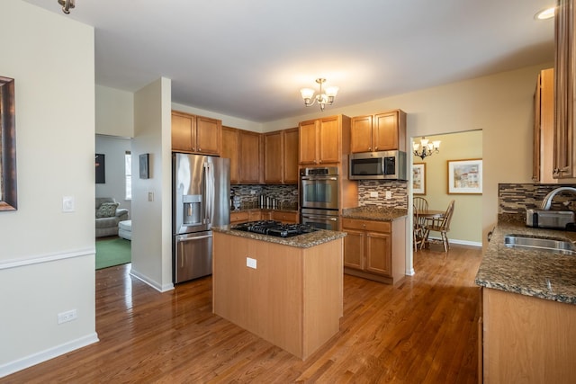 kitchen with a center island, stainless steel appliances, an inviting chandelier, dark stone countertops, and sink