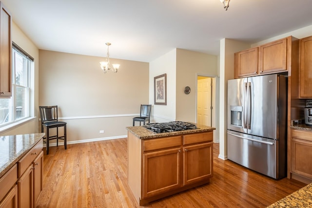 kitchen with black gas cooktop, light stone counters, pendant lighting, and stainless steel fridge with ice dispenser