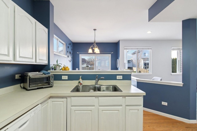 kitchen with dishwasher, sink, hanging light fixtures, light hardwood / wood-style flooring, and white cabinetry