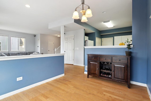 kitchen with dark brown cabinets, decorative light fixtures, an inviting chandelier, and light hardwood / wood-style floors