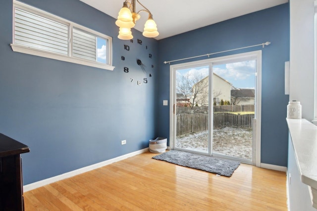 doorway to outside with hardwood / wood-style floors and a notable chandelier