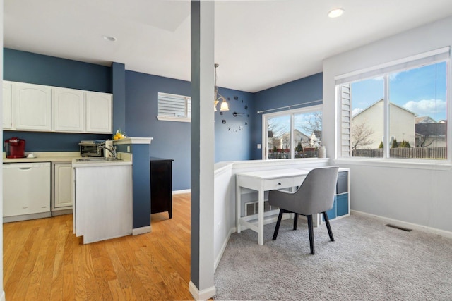 interior space with dishwasher, light wood-type flooring, white cabinetry, and hanging light fixtures