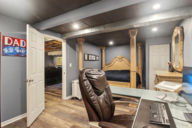 office area featuring decorative columns, light hardwood / wood-style floors, and beam ceiling