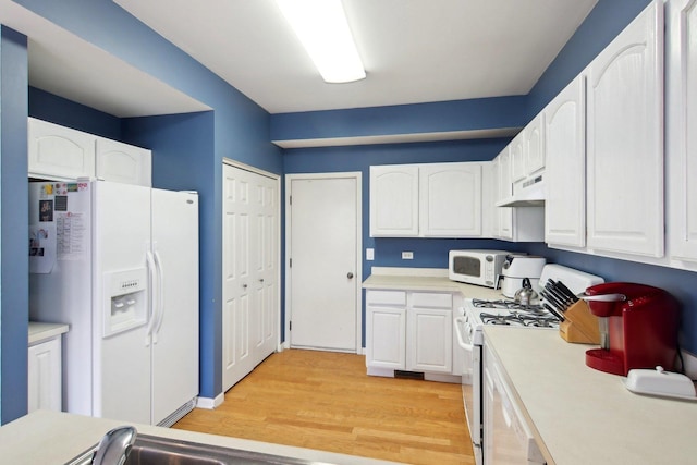 kitchen with custom exhaust hood, white cabinetry, light wood-type flooring, and white appliances