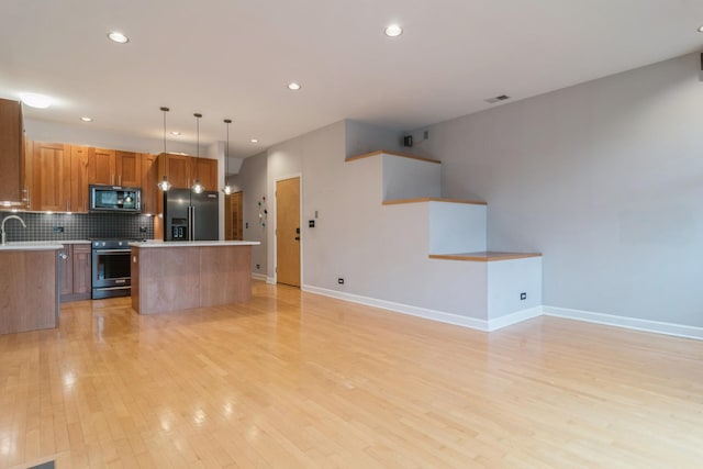 kitchen with decorative backsplash, refrigerator with ice dispenser, decorative light fixtures, a center island, and stainless steel electric range