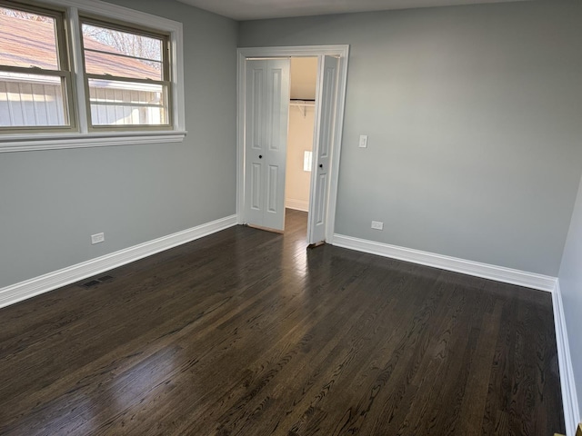 unfurnished bedroom featuring a closet and dark wood-type flooring