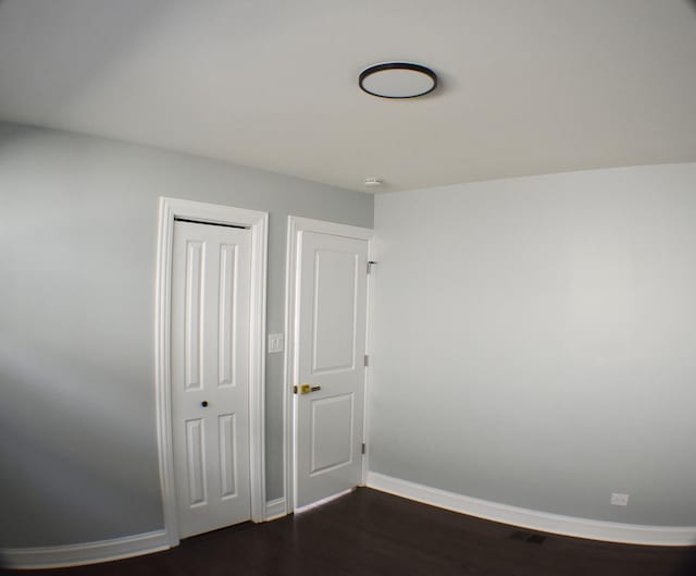 unfurnished bedroom featuring a closet and dark wood-type flooring