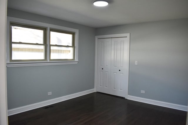 unfurnished bedroom featuring dark hardwood / wood-style floors and a closet