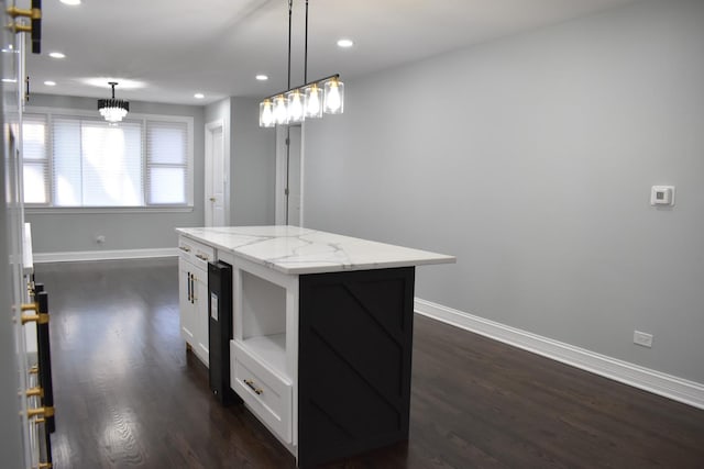 kitchen with white cabinetry, a center island, hanging light fixtures, light stone counters, and dark hardwood / wood-style flooring