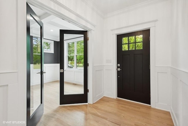 entryway featuring french doors, ornamental molding, and light wood-type flooring