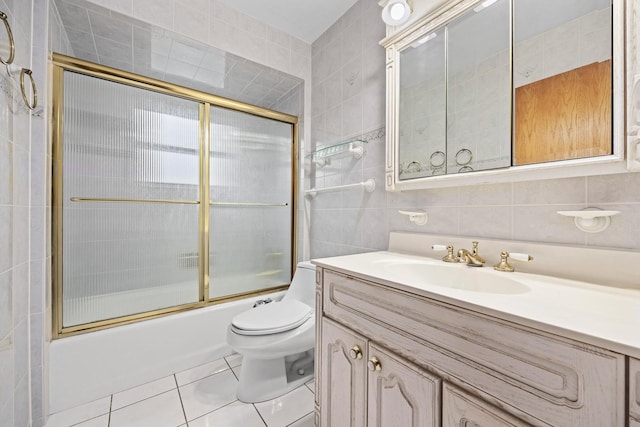 full bathroom with vanity, combined bath / shower with glass door, tile patterned flooring, toilet, and tile walls