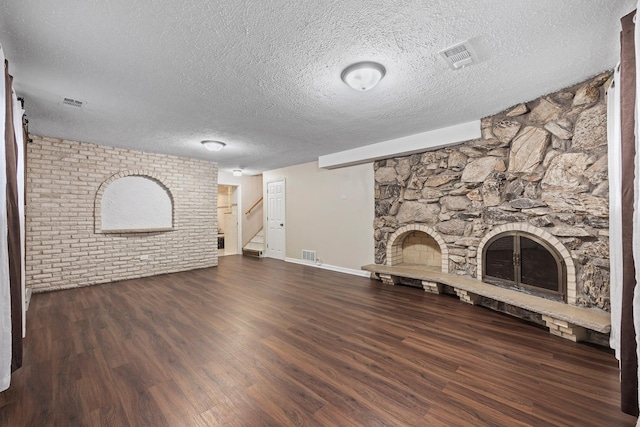 unfurnished living room with dark hardwood / wood-style flooring, a fireplace, and a textured ceiling