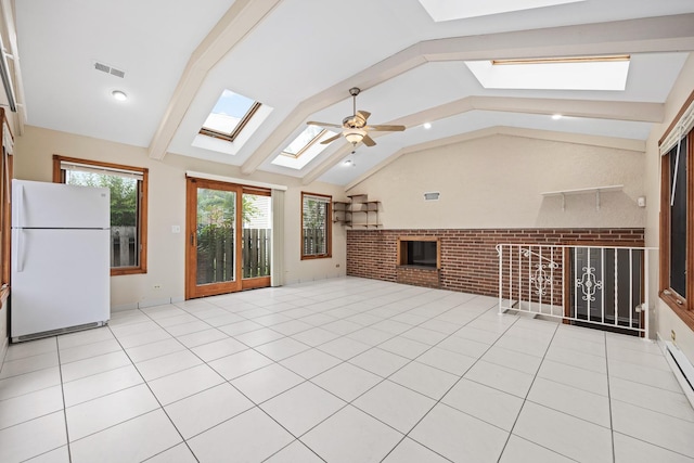 unfurnished living room featuring a fireplace, ceiling fan, vaulted ceiling with skylight, and light tile patterned flooring