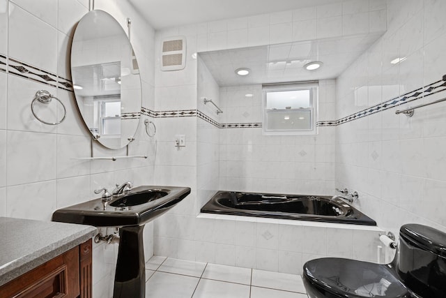 bathroom with tiled tub, tile patterned flooring, tile walls, and toilet