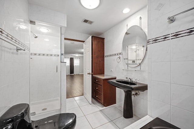 bathroom featuring tile patterned flooring, toilet, tile walls, and an enclosed shower