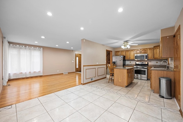 kitchen with ceiling fan, a center island, sink, light tile patterned flooring, and appliances with stainless steel finishes