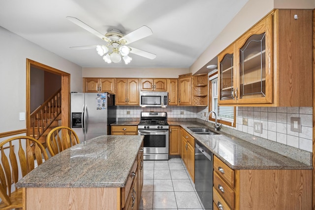 kitchen featuring stainless steel appliances, ceiling fan, sink, light tile patterned floors, and a kitchen island