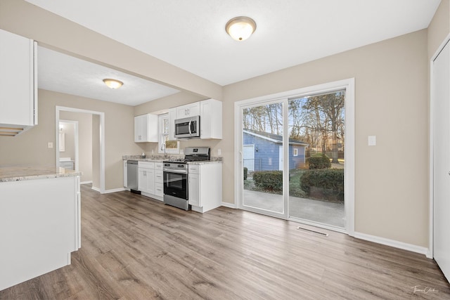 kitchen with sink, light hardwood / wood-style flooring, light stone counters, white cabinetry, and stainless steel appliances