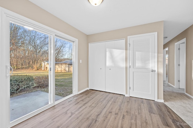 interior space with light hardwood / wood-style floors, access to outside, and multiple closets