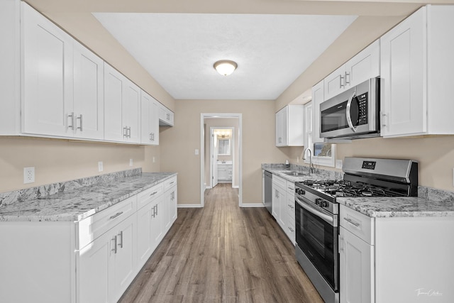 kitchen featuring light stone countertops, white cabinetry, sink, and stainless steel appliances