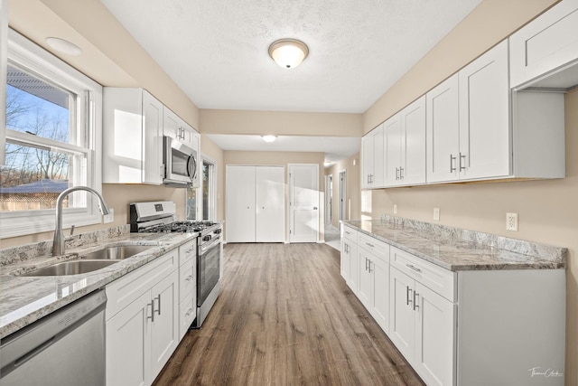 kitchen with a textured ceiling, stainless steel appliances, dark wood-type flooring, sink, and white cabinetry