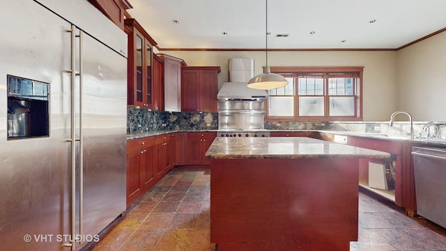 kitchen featuring light stone countertops, hanging light fixtures, stainless steel appliances, wall chimney range hood, and a kitchen island