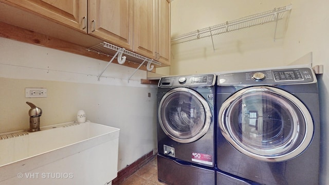 washroom with sink, dark tile patterned flooring, washer and dryer, and cabinets