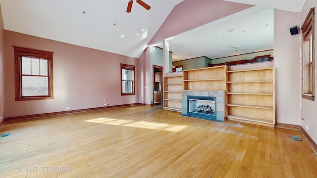 unfurnished living room featuring ceiling fan, hardwood / wood-style floors, vaulted ceiling, and a tiled fireplace