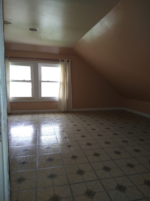 additional living space featuring light tile patterned floors and vaulted ceiling