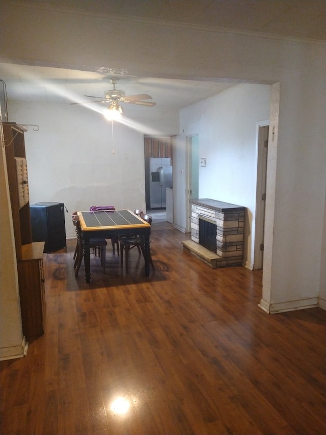 dining space with a fireplace, dark hardwood / wood-style flooring, ceiling fan, and ornamental molding