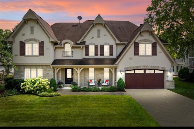 view of front of property featuring covered porch, a garage, and a yard