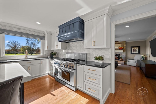 kitchen featuring white cabinets, sink, custom range hood, and range with two ovens