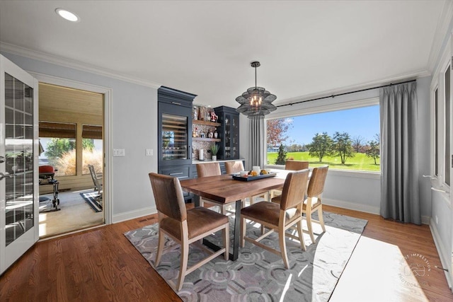 dining space with ornamental molding, a chandelier, and light hardwood / wood-style floors