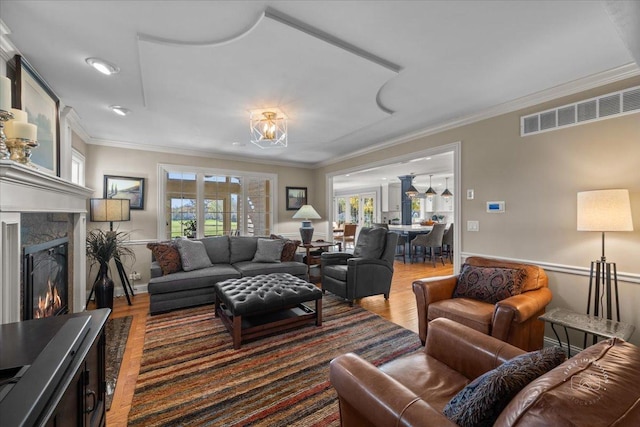 living room with hardwood / wood-style flooring, crown molding, and a fireplace