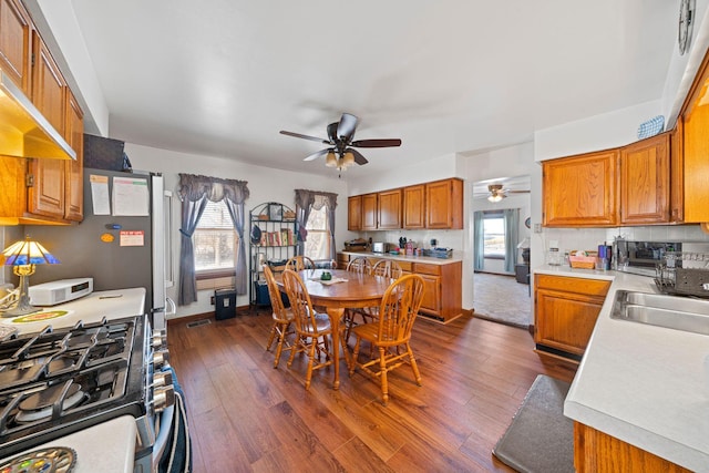 kitchen featuring sink, stainless steel gas range oven, dark hardwood / wood-style flooring, range hood, and backsplash